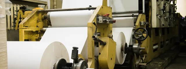 Rolls of newsprint feeding a newspaper printing press