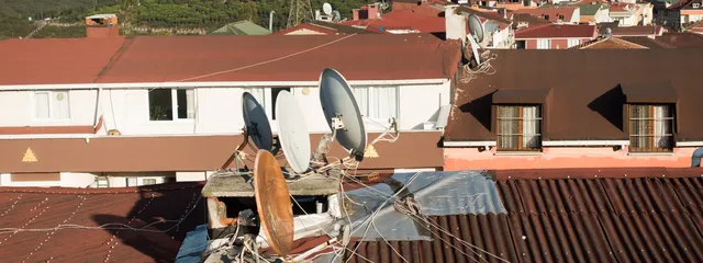 Satellite dishes on a rooftop in Istanbul, with the city's towers behind